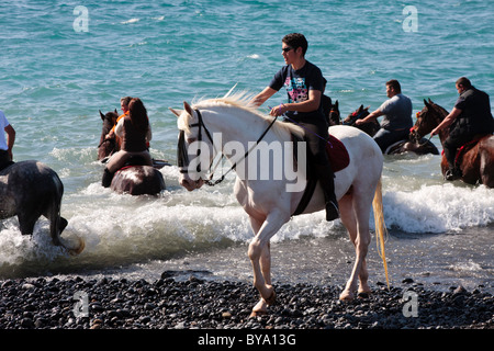 Piloti la balneazione i loro cavalli in mare a Adeje come parte dell'fiestas de San Sebastian, Tenerife, Isole Canarie, Spagna Foto Stock