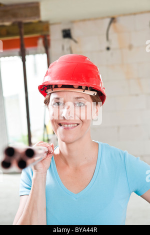 Craftswoman con elmetto per tubazioni di trasporto Foto Stock