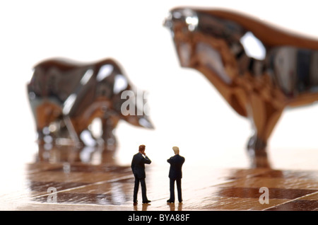 Due manager premuroso figurine a Bull e bear fuori fuoco dietro di loro, immagine simbolica Foto Stock