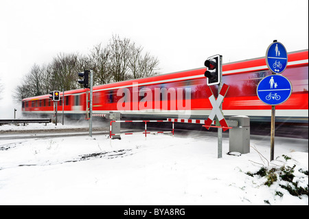 Treni passeggeri passando un passaggio a livello in inverno, Grevenbroich, Renania settentrionale-Vestfalia, Germania, Europa Foto Stock