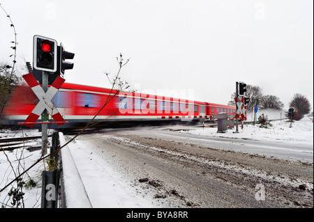 Treni passeggeri passando un passaggio a livello in inverno, Grevenbroich, Renania settentrionale-Vestfalia, Germania, Europa Foto Stock