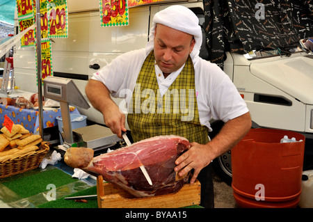 Venditore con prosciutto italiano Prosciuto o a un cavalletto di specialità sul mercato degli agricoltori, Roma, Lazio, l'Italia, Europa Foto Stock