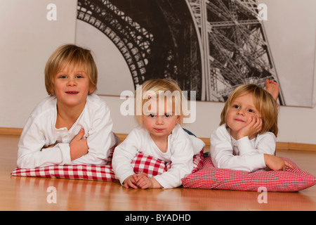 2 ragazzi di 7 e uno di 4 anni e una ragazza, 1,5 anni, sdraiato sul pavimento Foto Stock