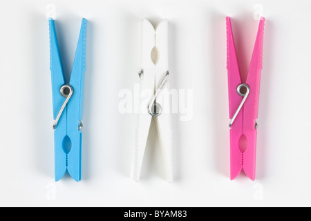 Tre in plastica colorata clothespins; sul bianco. Foto Stock