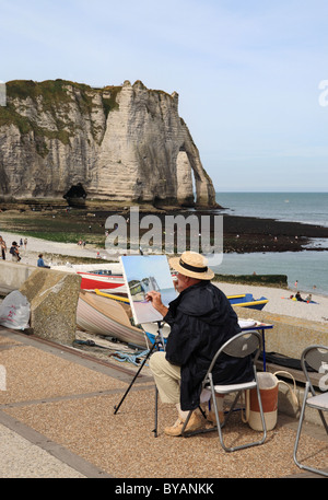 Un artista facendo una pittura delle scogliere tra cui la Falaise d'Aval o arco e la Aiguille o ago a Etretat in Normandia Foto Stock