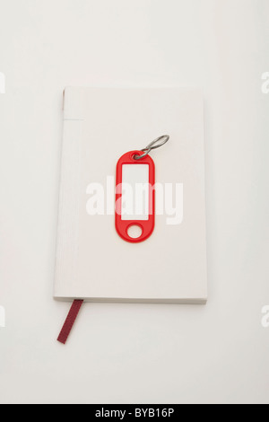 Notebook e key tag, immagine simbolica per la ricerca di un appartamento Foto Stock