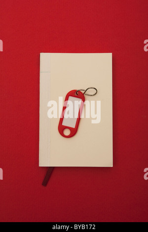 Notebook e key tag, immagine simbolica per la ricerca di un appartamento Foto Stock