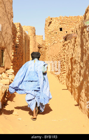 Uomo che cammina attraverso i vicoli di sabbia della città di Chinguetti, Mauritania, Africa nord-occidentale Foto Stock