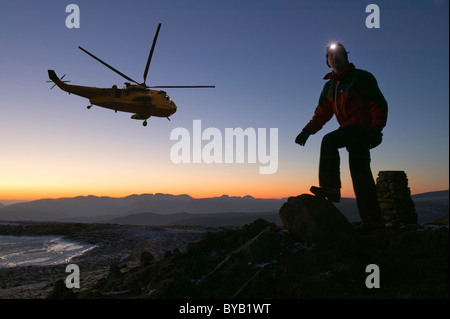 Un deambulatore su Red ghiaioni nel distretto del Lago Regno unito al crepuscolo, con un mare re elicottero. Foto Stock