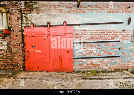 Vecchio, rosso porta scorrevole sul lato di una fabbrica/magazzino Foto Stock