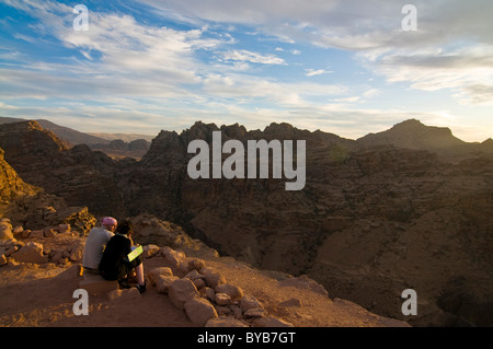Giovane che si affaccia sulle rocce vicino a Petra nel crepuscolo, Giordania, Medio Oriente Foto Stock