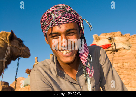 Sorridente uomo beduino, ritratto, con il suo cammello Wadi Rum, Giordania, Asia Occidentale Foto Stock