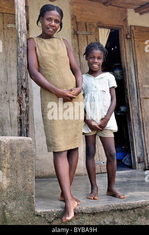 Madre e figlia di fronte alla loro semplice casa in legno, Petit Goave, Haiti, dei Caraibi e America centrale Foto Stock