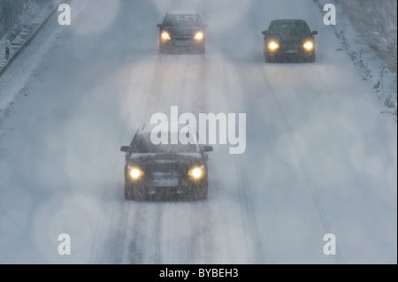 Tre vetture guida in una neve flulrry su una autostrada Foto Stock