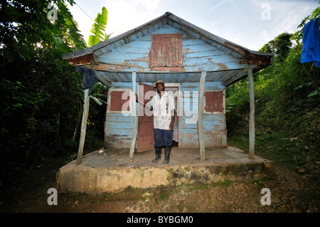 L'uomo di fronte al suo tradizionale casa di legno che è stata gravemente danneggiata dal terremoto del gennaio 2010, villaggio nei pressi di Jacmel Foto Stock