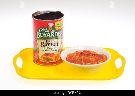 Ciotola di Chef Boyardee Ravioli di carne in una ciotola bianca con lattina vuota sul vassoio giallo su sfondo bianco tagliato fuori Foto Stock