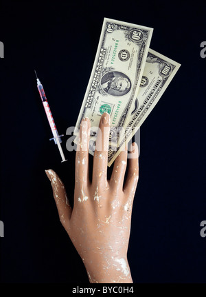 MANO FITTIZIA DERELICT CON BANCONOTE DA 50 E 100 DOLLARI USA E AGO IPODERMICO Foto Stock