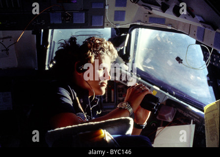 Astronauta Kathryn D. Sullivan utilizza un binocolo per una visualizzazione ingrandita della Terra attraverso Challenger la cabina di prua di windows. Foto Stock