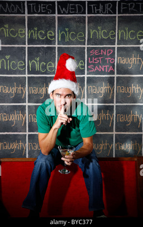 Elf uomo di fronte naughty e Nizza dicembre Natale calendario con un martini in mano. Foto Stock