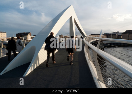 I pedoni che camminano correndo a casa attraverso il ponte pedonale dopo il lavoro su un Serata d'autunno Glasgow Scozia Gran Bretagna KATHY DEWITT Foto Stock