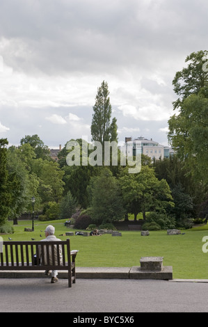 Un uomo seduto su una panchina di fronte al Museo dello Yorkshire, che si affaccia sul giardino botanico. Foto Stock
