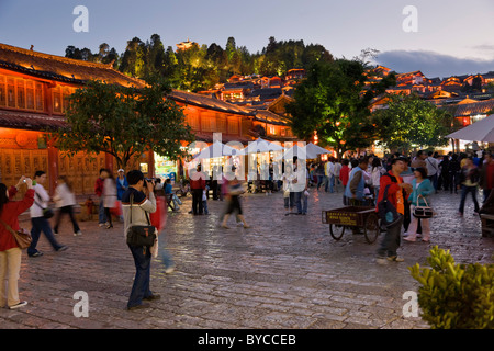 Crepuscolo con luci accese in lastricato in pietra antica piazza del mercato a Lijiang old town, nella provincia dello Yunnan in Cina. JMH4760 Foto Stock