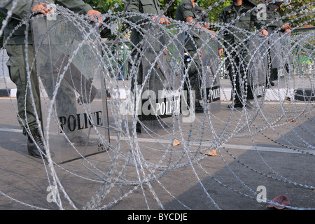 Polizia dietro al filo spinato guard un ingresso al Palazzo del Governo di Bangkok durante un grande governo anti-giallo-shirt rally Foto Stock