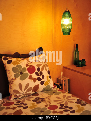 Posto letto sospeso in vetro verde lampada, comodino con bicchieri e bottiglie e libri Foto Stock