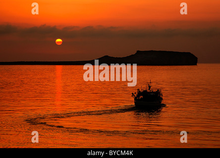 Una barca da pesca lasciando il piccolo porto di mare insediamento di Mezapos in mani, intorno al tramonto. La Laconia, Peloponneso, Grecia Foto Stock