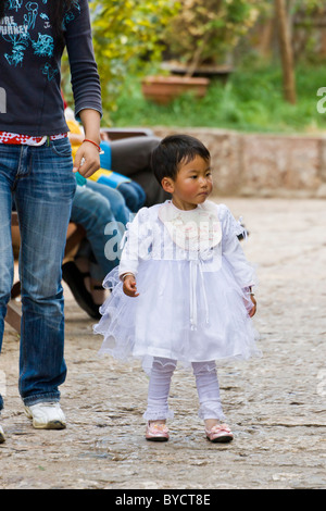 Era bellissima e molto giovane cinese bambina indossa lacy abito bianco a Lijiang old town, nella provincia dello Yunnan in Cina. JMH4773 Foto Stock