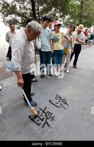 Il vecchio uomo cinese praticare street calligraphy nella motivazione del nuovo Palazzo Estivo, Pechino, Cina. JMH4797 Foto Stock