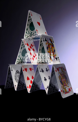 Piramide di carte da gioco. 14 carte sovrapposte in modo da formare una piramide con luce blu - sfondo blu scuro. Foto Stock