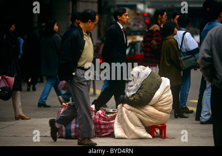 I passanti da ignorare i bisognosi bag-lady in Hong Kong Tsim Sha Tsui street sul lato di Kowloon. Foto Stock