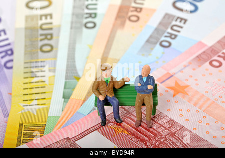 Miniatura figure di anziani su una panchina nel parco su varie banconote in euro, immagine simbolica per la pensione e Foto Stock