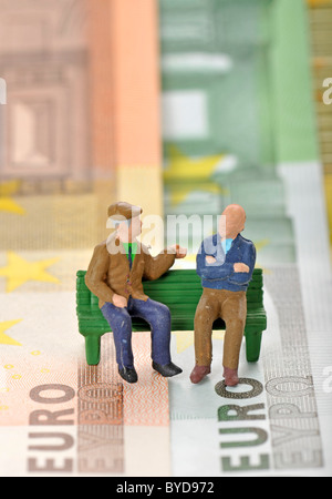 Miniatura figure di anziani su una panchina nel parco su varie banconote in euro, immagine simbolica per la pensione e Foto Stock