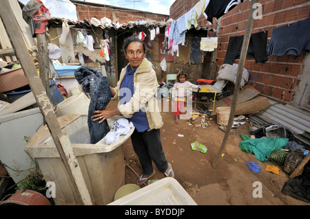 Donna incinta, 43, lavare i panni nella parte anteriore di una squallida baracca in una Favela o bidonville, vive la famiglia raccogliendo, Foto Stock