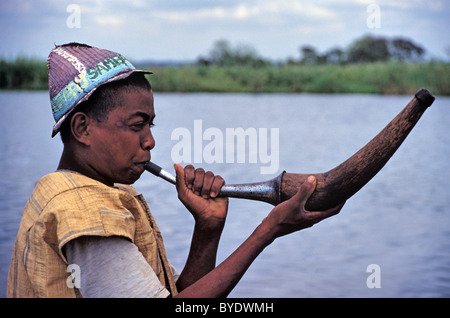 Uomo malgascio la riproduzione o la soffiatura di corno, suonatore di corno, alla circoncisione Sambatra Festival dalla Pangalanes Canal, Mananjary, Madagascar Foto Stock