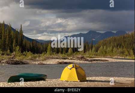 Camp sulla ghiaia bar, tenda e canoa, Pelly montagne dietro, superiore Liard River, Yukon Territory, Canada Foto Stock