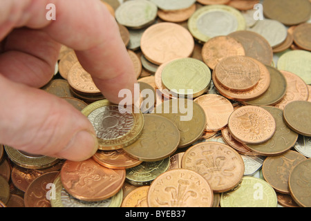 Un dito e il pollice il prelievo di una sterlina GBP 2 moneta da una ridda di monete Foto Stock