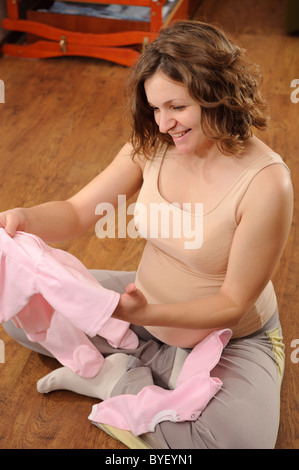 Giovane donna incinta con il suo futuro del bambino vestiti Foto Stock