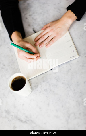 La donna la scrittura sul diario, caffè sul lato Foto Stock