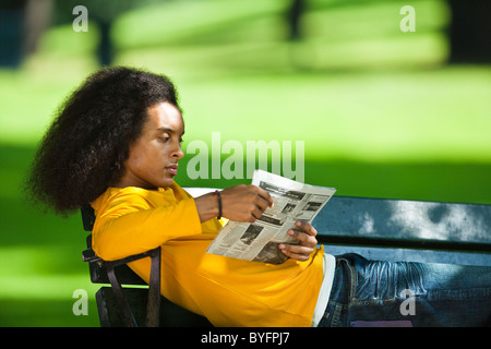 Giovane uomo con capelli afro quotidiano di lettura sul banco di lavoro Foto Stock