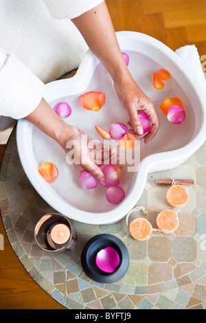 Close up di mani petali di rosa nella ciotola in spa Foto Stock