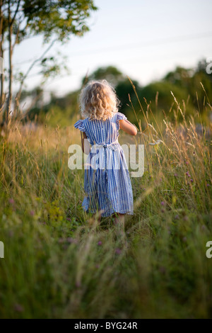 Ragazza in piedi sul prato, vista posteriore Foto Stock