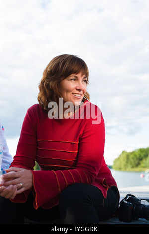 Donna seduta sul molo e sorridente Foto Stock