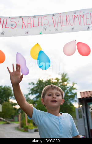 Ragazzo agitando sotto il banner di benvenuto Foto Stock