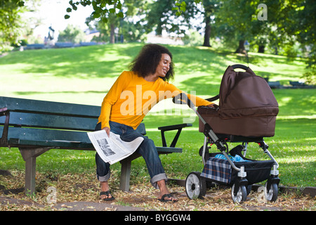 Sorridente giovane con bambino trasporto seduta sul banco di lavoro Foto Stock