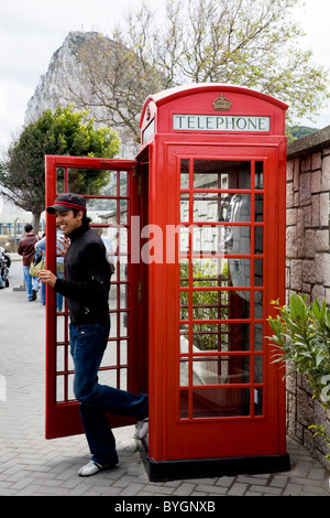 Giovane uomo / tourist lasciando un originale K6 telefono rosso / telefono call box su Gibilterra, vicino al confine con la Spagna. Rocca di Gibilterra. Foto Stock