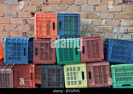 Cassette in plastica e un muro di mattoni dello sfondo. Pila di frutta colorati contenitori per imballaggio. Foto Stock