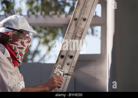 Proprietario della pittura la parte esterna di un unica famiglia, ranch stile home in San Jose, CA prima di mettere la casa in vendita. Foto Stock